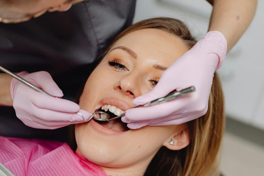 pexels-photo-6627523-6627523-1 Female patient receiving a dental examination with instruments at a clinic.